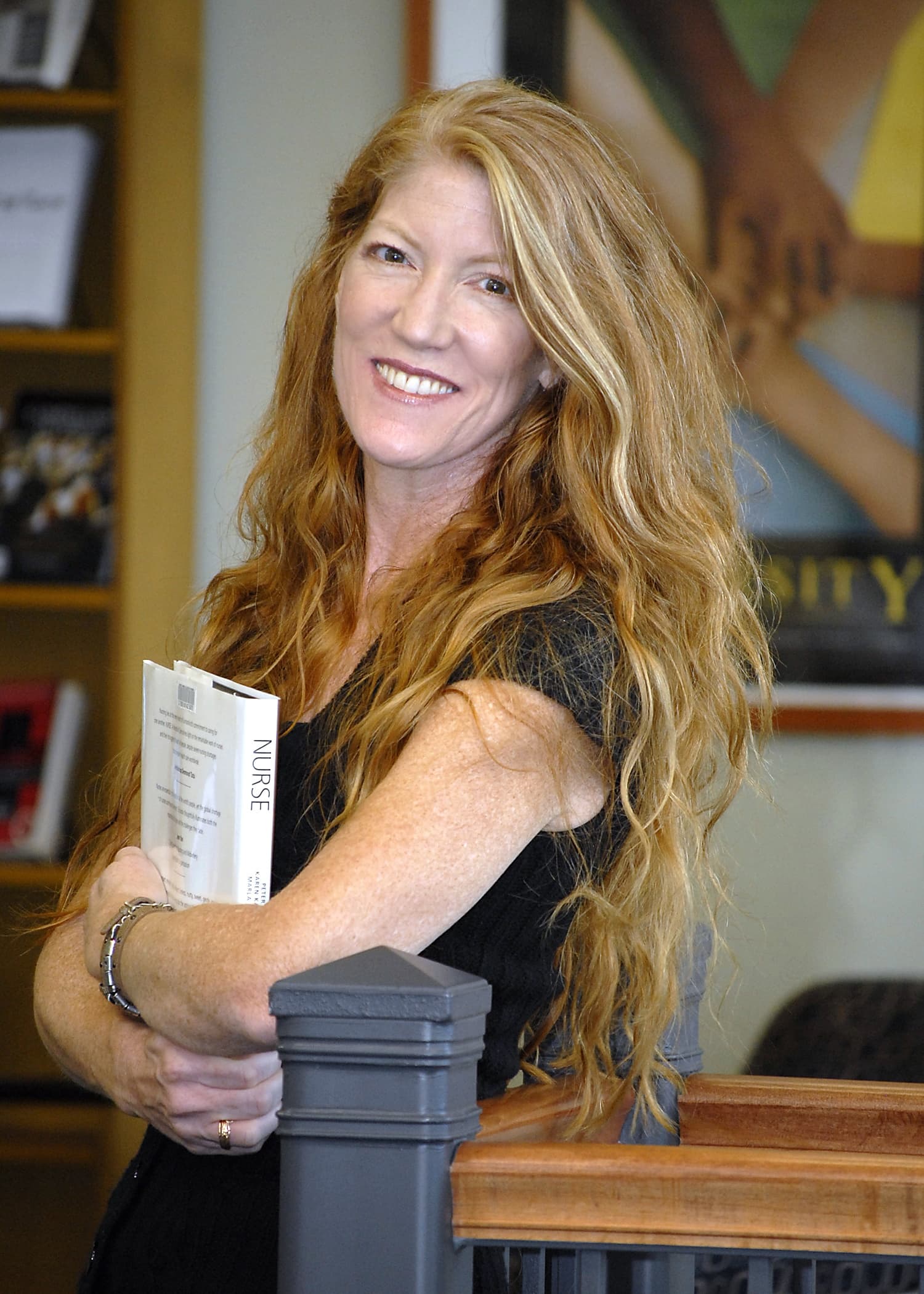 Tina Marie Cerra, red-gold hair, smiling and holding a book titled Nurse